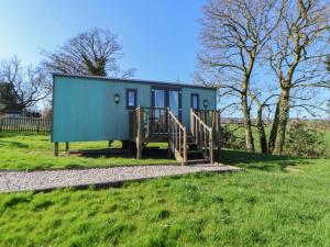 a green tiny house on a grassy field at Shepherds Delight in Macclesfield