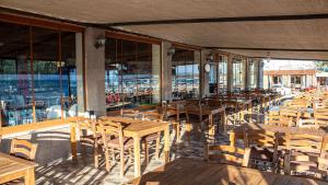 a restaurant with wooden tables and chairs and windows at Sivrice Sarnıç in Behramkale +4 photos