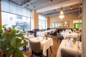 a restaurant with white tables and chairs and windows at Hotel Astoria in Olten