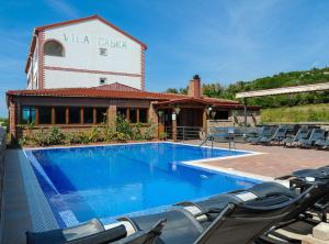 a swimming pool with chairs in front of a building at Golden Coast Villa Caska in Novalja