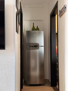 a stainless steel refrigerator with two bottles on top of it at Flat Romance Praia e Home Office in São Vicente