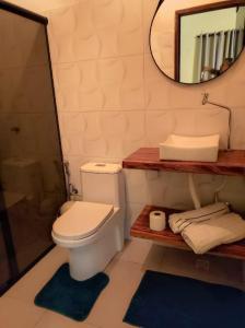 a bathroom with a toilet and a mirror and towels at Chalé Corina in Pirenópolis +19 photos