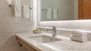 a white bathroom with a sink and a mirror at Hotel Noto Marina Scirocco & SPA in Noto Marina +16 photos