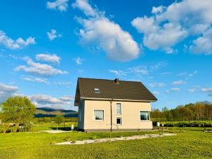 a house with a black roof on a green field at Polny Domek in Bystrzyca Kłodzka