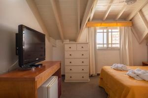 a bedroom with two beds and a flat screen tv at Belmar in Villa Gesell