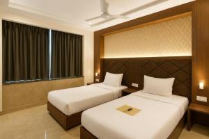 a hotel room with two beds and a window at Glitz Saineel Executive Near Juhu Beach in Mumbai