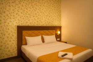 a bedroom with a bed with a remote control on it at Glitz Saineel Executive Near Juhu Beach in Mumbai