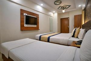 a hotel room with two beds and a tv at Glitz Saineel Executive Near Juhu Beach in Mumbai +2 photos
