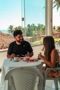 a man and a girl sitting at a table at Mansão do Kite - Praia do Coqueiro in Luis Correia