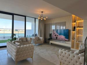 ein Wohnzimmer mit Sofas und einem Flachbildfernseher in der Unterkunft Beachfront Villa with Heated Private Pool & Jacuzzi in Al Ḩamrīyah