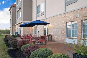 a patio with chairs and a table with an umbrella at Garner Hotel Houston - Westchase by IHG in Houston