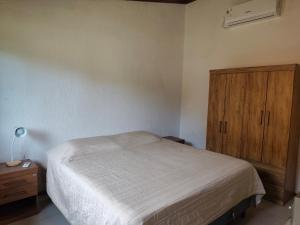a bedroom with a bed and a wooden cabinet at Cabaña la Tijereta del Iporá in Balneario Ipora