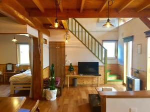 ein Wohnzimmer mit einem Bett, einem TV und einer Treppe in der Unterkunft Country Cottage Wakiaiai in Nakafurano