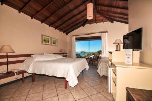 a bedroom with a bed and a flat screen tv at Aguabúzios Hotel in Búzios