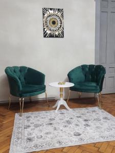 two green chairs and a table in a living room at Central old town escape in Timişoara
