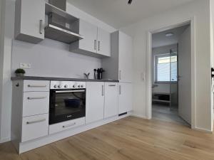 a kitchen with white cabinets and a stove at Zippel`s Fewo M14 in Bad Buchau
