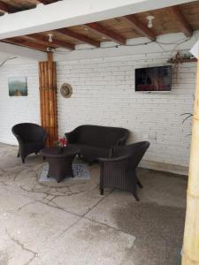 a patio with three wicker chairs and a couch at Hotel Piedra del Mar in Puerto López