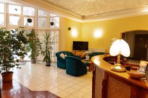 a living room with yellow walls and green chairs at Hotel Penta Lux in Tata