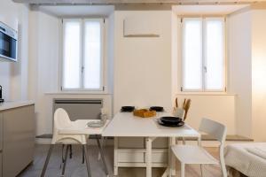 a white kitchen with a white table and chairs at Cà del Lago in Arona +25 photos