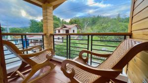 a balcony with three chairs and a view of a farm at Riverfront Paradise Villa River front Villa in Jarabacoa