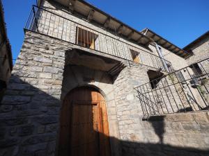 a stone building with a wooden door and a balcony at Casa Ara in Boltaña