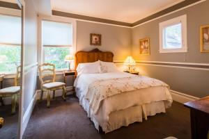 a bedroom with a bed and a desk and two windows at Inn St Helena in St. Helena