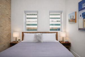 a bedroom with a bed with two lamps and two windows at Luxury Downtown 2 Bedroom Flat in Neenah