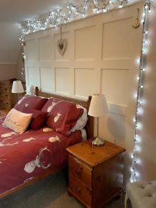 a bedroom with a bed with a headboard and lights at Meadow Cottage in Crieff