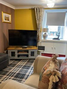 a living room with a large flat screen tv at Meadow Cottage in Crieff