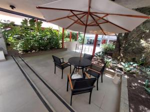 a patio with a table and chairs and an umbrella at Flat Jardins, Paulista, Oscar Freire, restaurantes in São Paulo