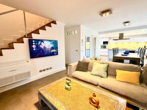 a living room with a couch and a tv on a wall at Famara ocean view house in Famara