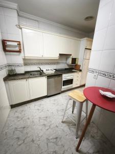 a kitchen with white cabinets and a red table at Aires do Masma in Foz