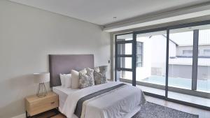 a white bedroom with a bed and a large window at Pops lifestyle in Sandton +44 photos