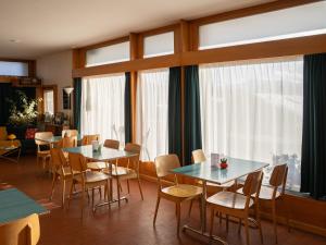 a dining room with tables and chairs and windows at Hôtel historique Chez Elsy - Crans-Sapins in Crans-Montana