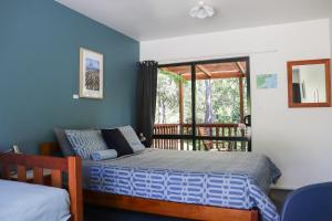 a bedroom with a bed and a balcony at Kanuka Ridge Lodge in Marahau