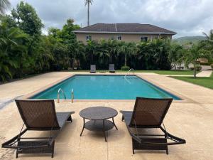 two chairs and a table next to a swimming pool at Ubuntu De La Villa- Palm View Estate in Mammee Bay