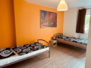 two beds in a room with orange walls at StayHere24 Große Monteur- und Ferienwohnung am Auenwald in Schkeuditz