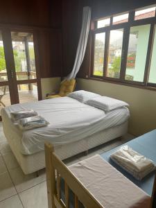 a bedroom with two beds and two windows at Guarda Flats in Guarda do Embaú