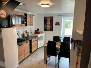 a kitchen with a table and black chairs in it at Logement indépendant à la campagne proche du Pôle européen du Cheval et Circuit des 24h du Mans in Courceboeufs