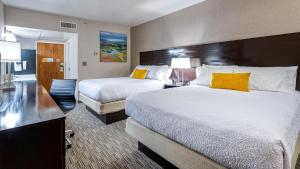 a hotel room with two beds with yellow pillows at University Inn in Logan +25 photos