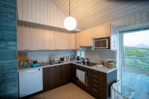 a kitchen with wooden cabinets and a large window at Arctic Panorama House in Lødingen +36 photos