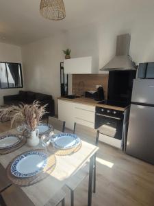 a kitchen and living room with a table with plates on it at JMAM Urban Suite T2 Climatisé en centre ville proche plage in Fos-sur-Mer