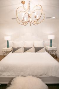 a bedroom with a white bed with a chandelier at Marée Mason in Ocean Springs +12 photos