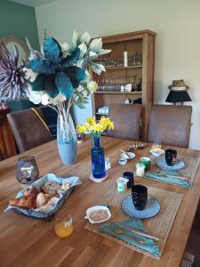 a wooden table with food and a vase of flowers at L'Essentiel in Oherville