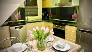 a kitchen with a table with pink flowers in a vase at Veløyveien 4b in Sandefjord