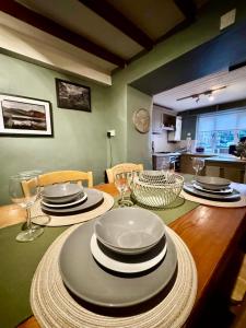 a dining room table with plates and wine glasses at Snowdon Retreat in Llanberis