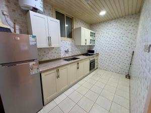 a kitchen with white cabinets and a stainless steel refrigerator at اكنان للشقق المفروشة in Buraydah
