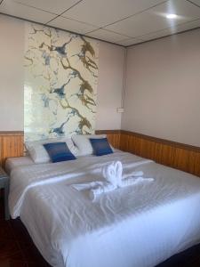a large bed with two white towels on it at Koh Samed Lungdam Hutbeach เกาะเสม็ดลุงดำฮัทบีช in Ao Phutsa