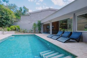 a swimming pool with two blue chairs next to a house at Casa Palma in Medellín