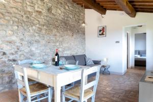 a dining room with a white table and a stone wall at Rustic House, con patio e giardino, Assisi centro in Assisi